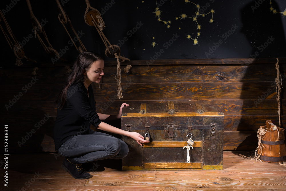 Young girl sits near a chest and trying to find a solution of conundrum to get out of the trap