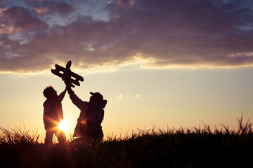 Father and son playing with cardboard toy airplane in the park at the day time.