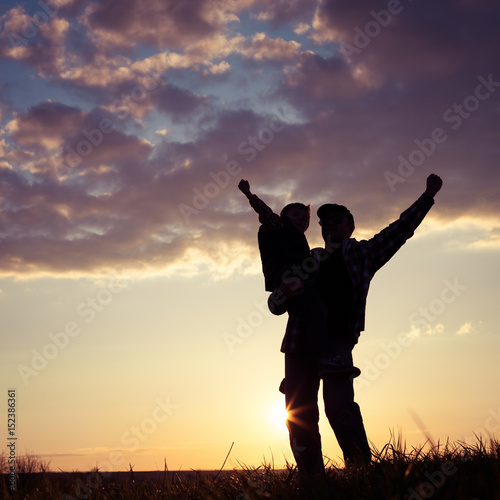 Father and son walking on the field at the sunset time.