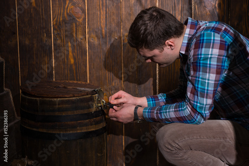 Young man sits near a barrel and trying to solve a conundrum to get out of the trap photo