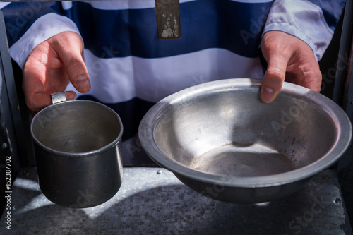 Prisoner s hands holding aluminum dishes in a hole for supplying food