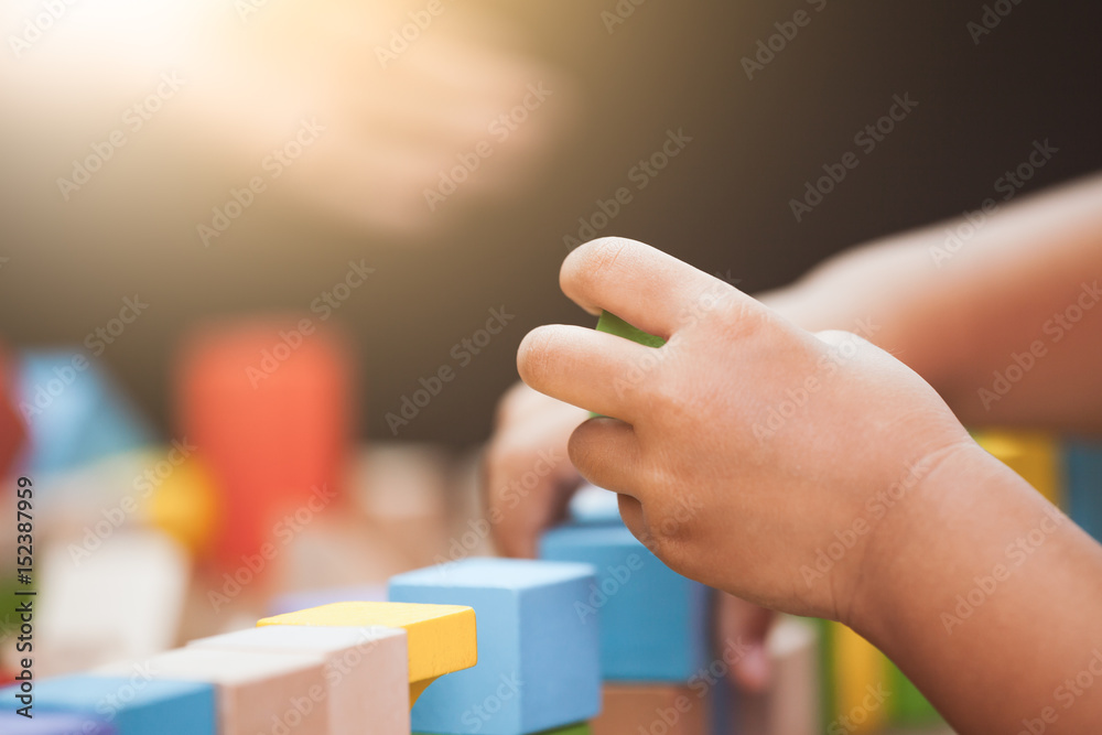 Focus on child's hand playing with colorful wooden blocks in vintage color tone Focus on child's hand playing with colorful wooden blocks in vintage color tone