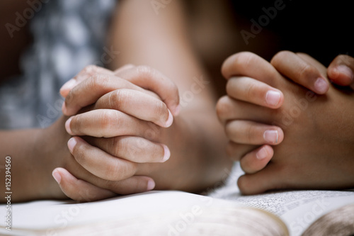 Two Little girl hands folded in prayer on a Holy Bible together  for faith concept in vintage color tone © pingpao