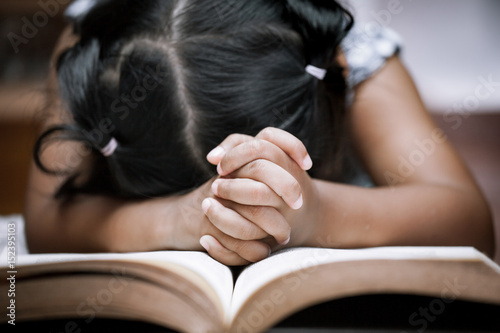 Sticker Little girl hands folded in prayer on a Holy Bible in church  for faith concept