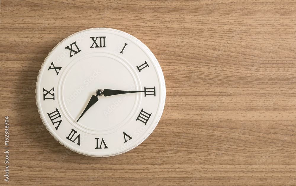 Closeup white clock for decorate show a quarter past seven o'clock or 7:15 a.m. on wood desk textured background with copy space Closeup white clock for decorate show a quarter past seven o'clock or 7:15 a.m. on wood desk textured background with copy space