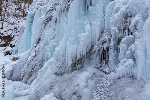 Wild river, beautiful frozen waterfalls and fresh snow in a mountain forest, on a cold winter day