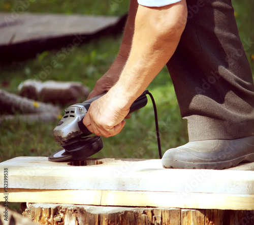 Hands of a man taking measurement of a wooden plank photo