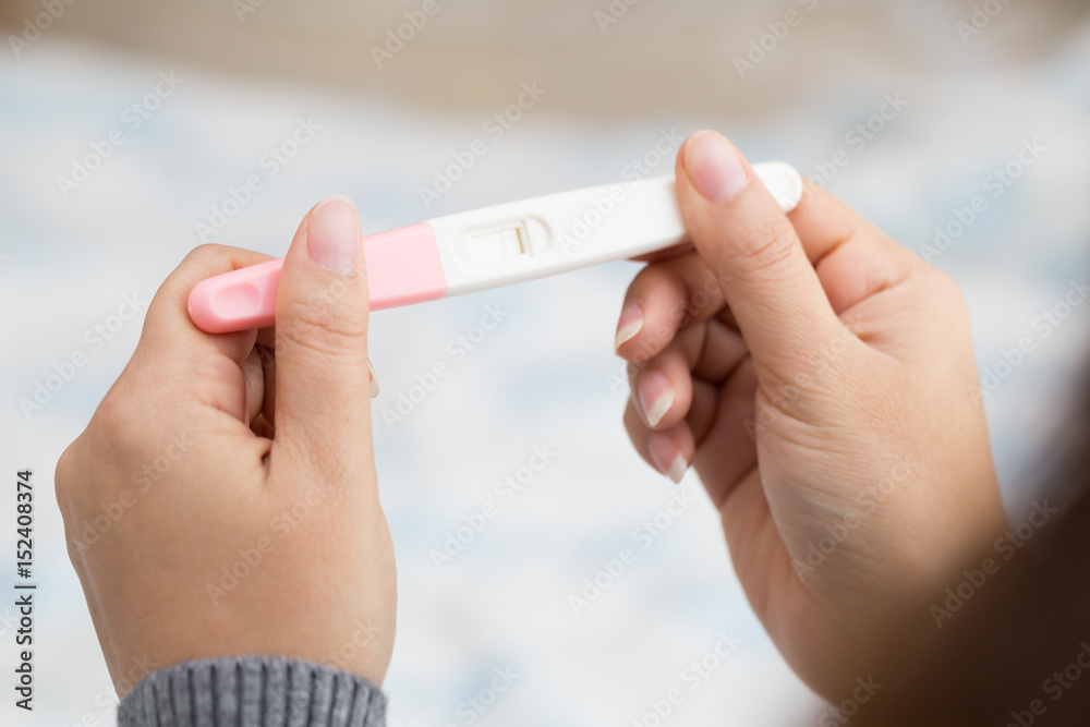 Woman hand holding pregnancy test and result is not pregnant - obrazy, fototapety, plakaty 
