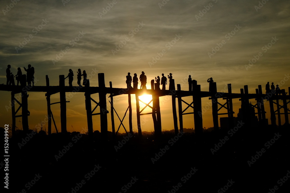Silhouettes of people walking on long wooden bridges in the world in Burma