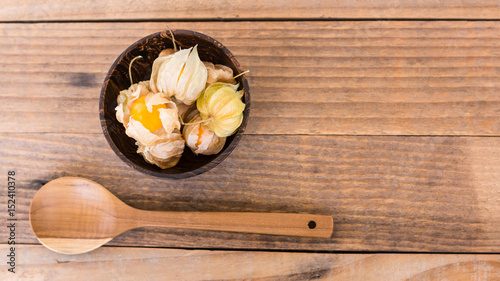 top view of cape gooseberry (Physalis) in wooden bowls and wooden spoon