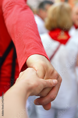 Go to festival San Fermin, Pamplona, Spain. Male and female hands over San Fermin street crowd. Man leads her woman in traditional spanish show. Fiesta, encierro, corrida concept.