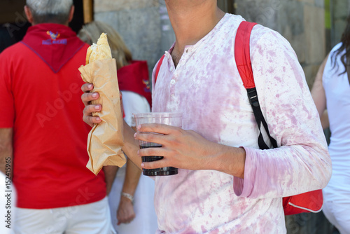Man in t-short in wine with fast food and wine, San Fermin festival, 06 July 2016, Pamplona, Navarra, Spain. photo