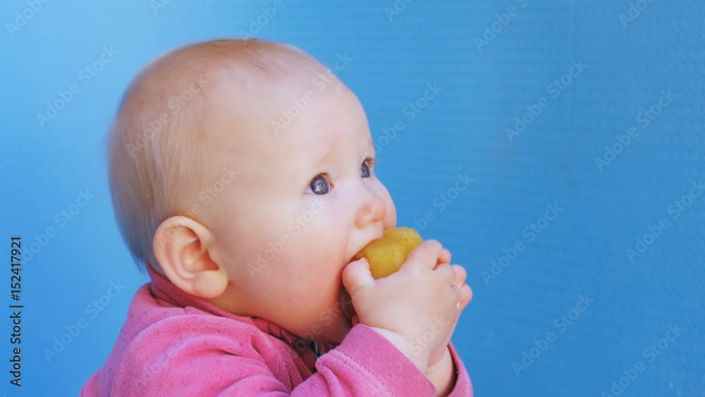 Baby eats peeled plum holding it in both hands Baby eats peeled plum holding it in both hands