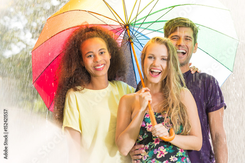 Happy friends under umbrella