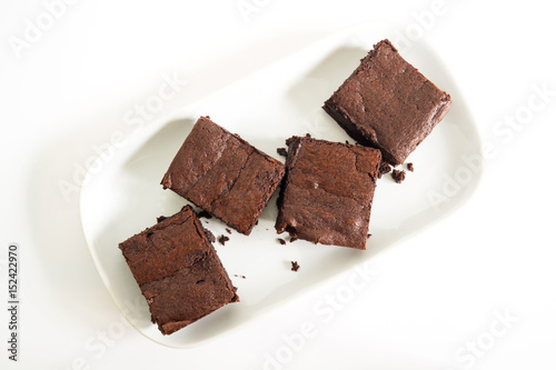 Sliced brownies on white plate over white background. Top view. Sweet and moist chocolate dessert.