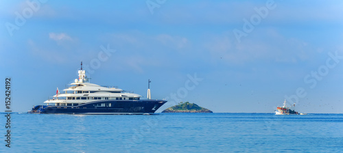 Luxusyacht und Fischerboot treffen sich im Meer © photobars