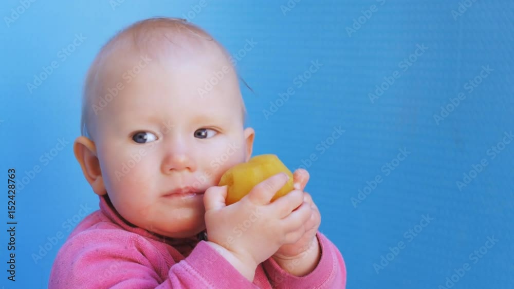 Baby eats peeled plum holding it in both hands Baby eats peeled plum holding it in both hands
