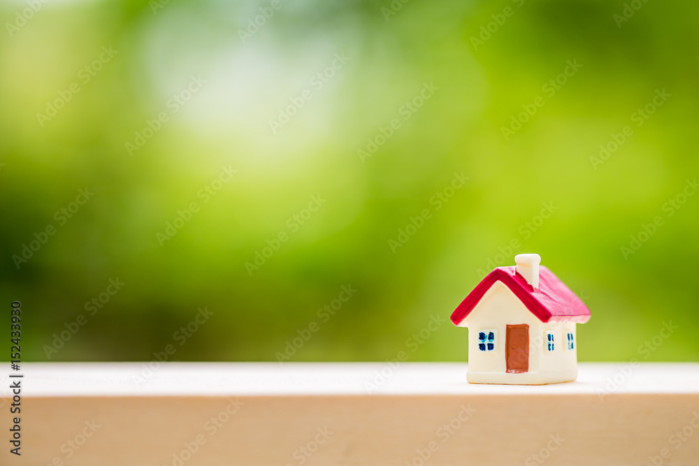 miniature house with red roof on wooden mock up over blurred green garden miniature house with red roof on wooden mock up over blurred green garden