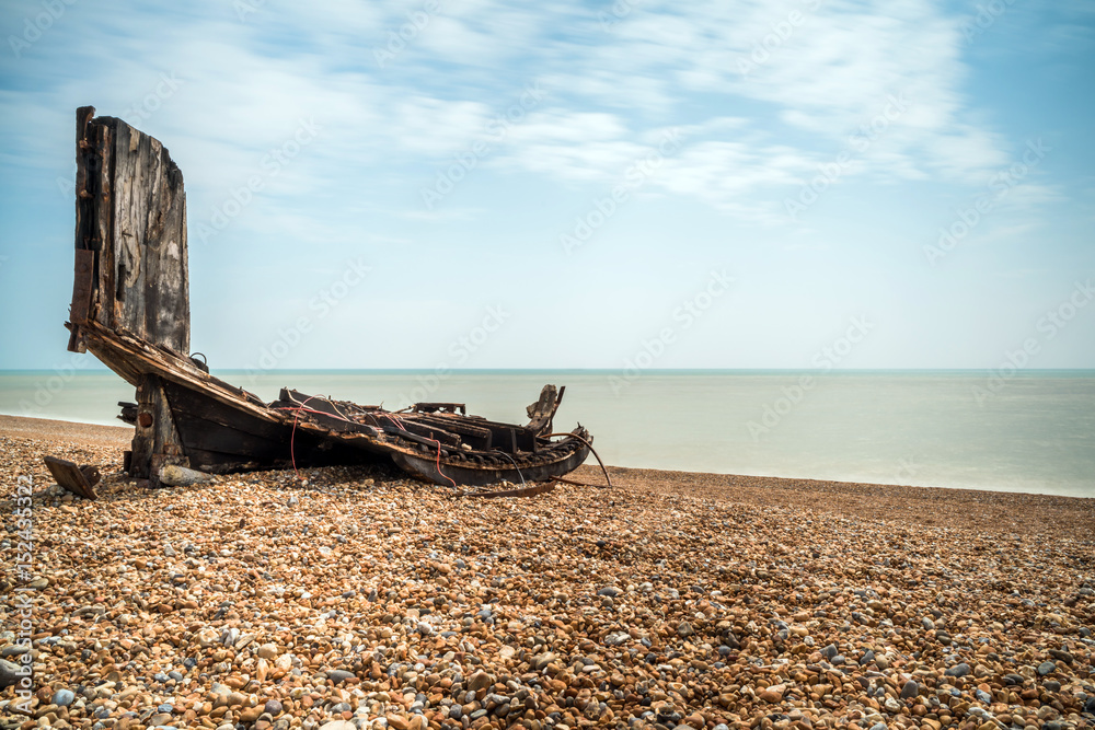 Remains an old wooden fishing boat on stony beach in Hastings, East Sussex, UK