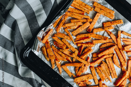 Baked sweet potatoes fries on black backing plate