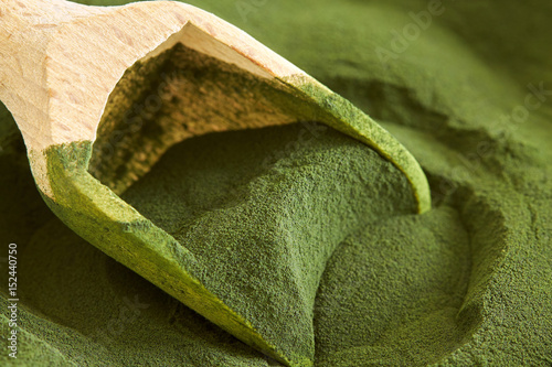Closeup of chlorella algae powder with wooden scoop