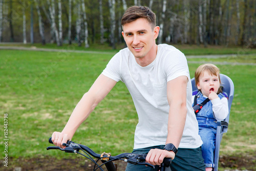Father and daughter ride a bicycle in the park