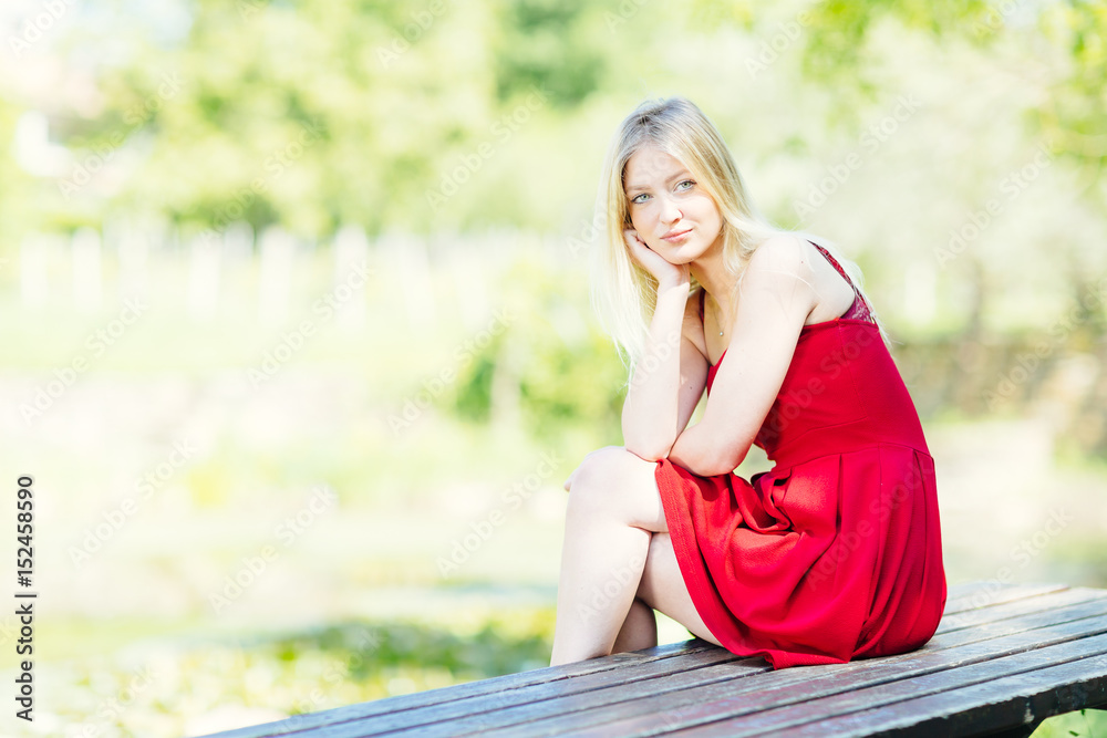 Young blonde woman sitting on the table in the park. Teenager fashion lifestyle. Young blonde woman sitting on the table in the park. Teenager fashion lifestyle.