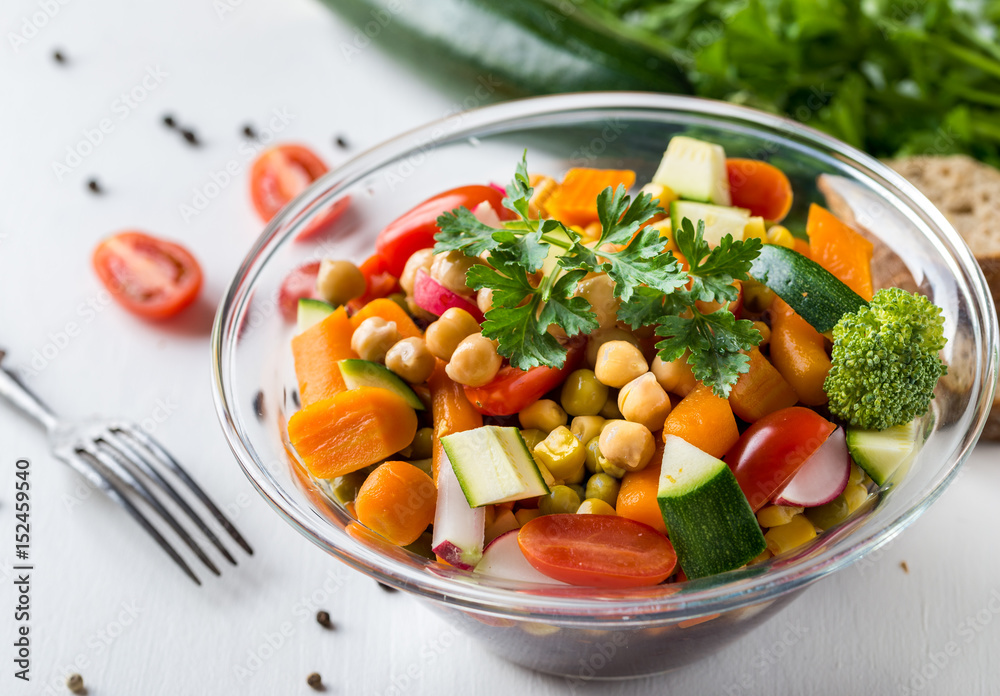 Vegetable salad in glass bowl with broccoli and tomatoes on white table. Vegetable salad in glass bowl with broccoli and tomatoes on white table.