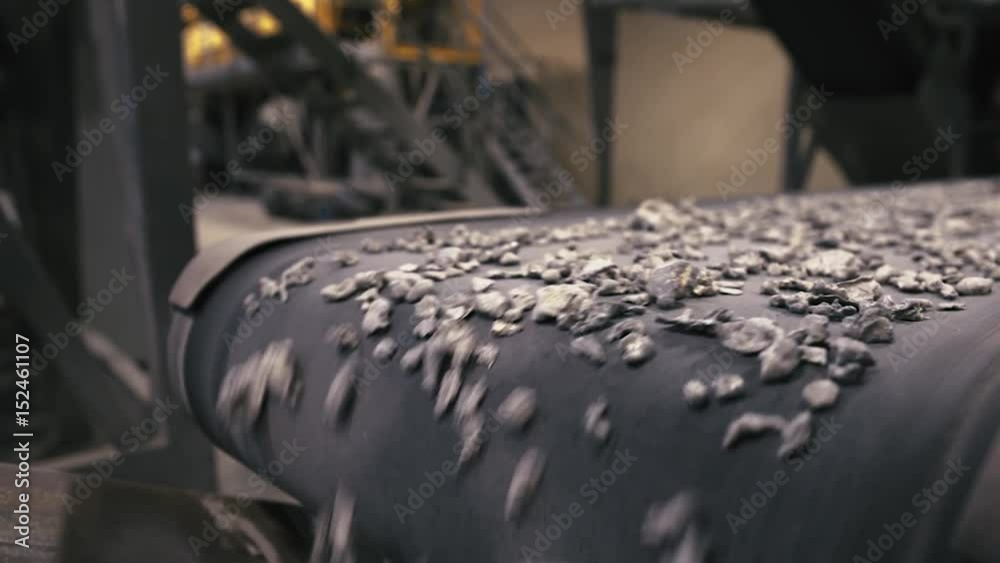 Recycling Facility.  Close-up of assembly line with metal waste on, employee sorting the wasteClose-up of assembly line with metal waste on, employee sorting the waste