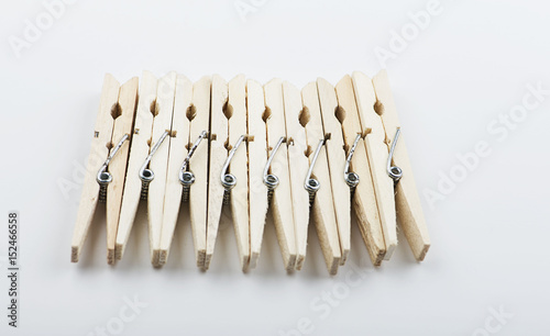 Wooden clothespins lined up on white background. Isolated.