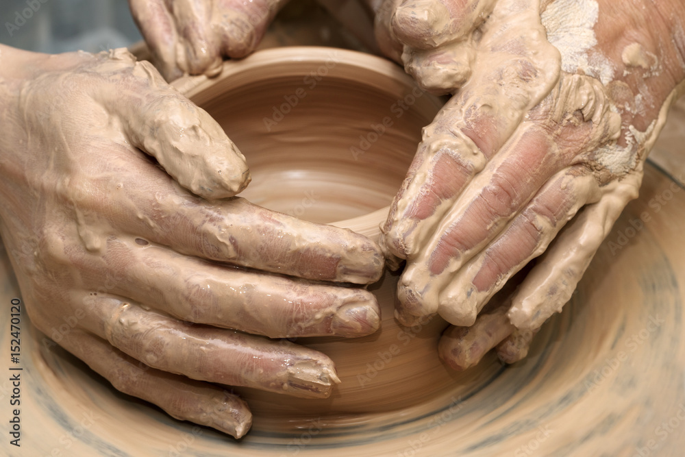 Women hands in clay at process of making  crockery on pottery wheel