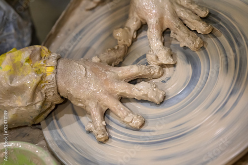 Hands of young girl in clay on pottery wheel