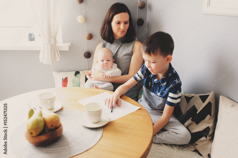 happy young mother having breakfast in kitchen with her baby daughter and kid son happy young mother having breakfast in kitchen with her baby daughter and kid son