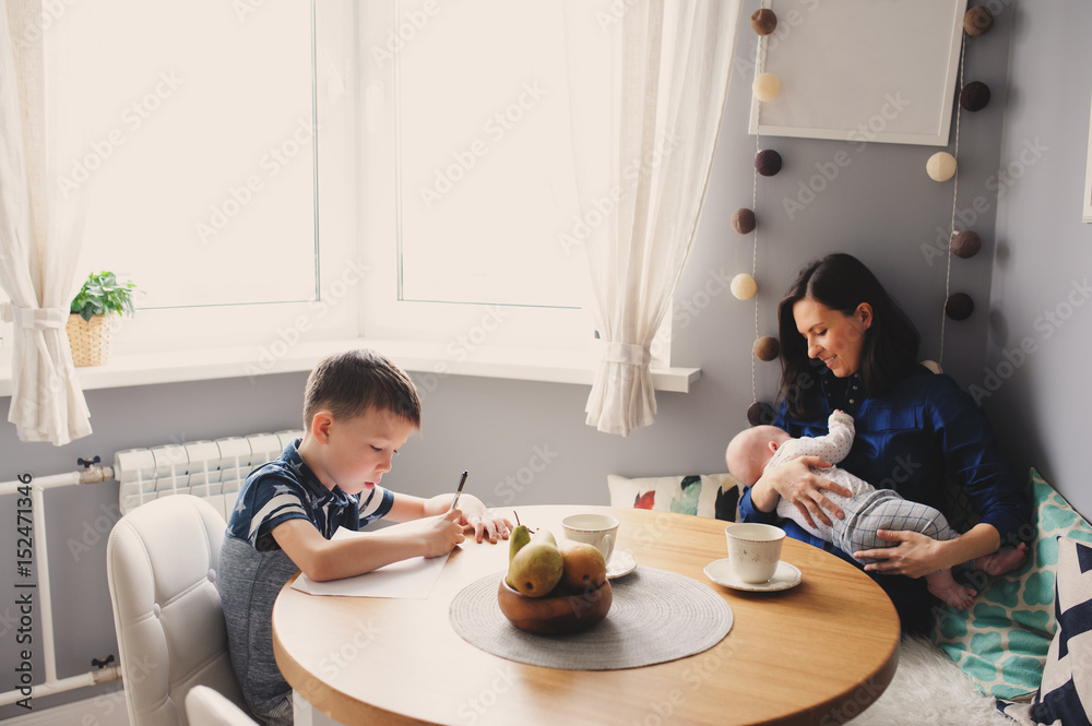happy young mother having breakfast in kitchen with her baby daughter and kid son happy young mother having breakfast in kitchen with her baby daughter and kid son