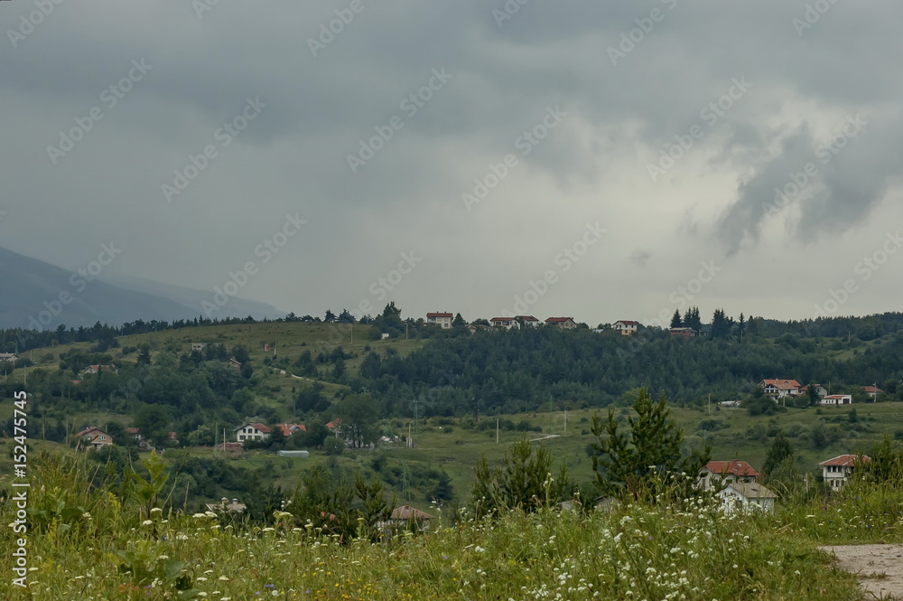 Scene with mountain glade, forest and residential district of bulgarian village Plana, Plana 

mountain, Bulgaria 