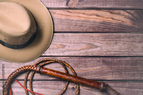 Travel and adventure concept. Vintage fedora hat and bullwhip on wooden table. Top view