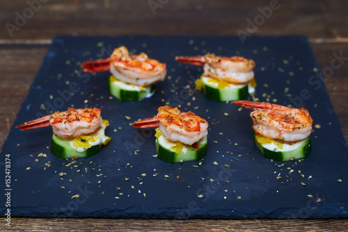 Well-cooked aromatic shrimps on grilled zucchinis with white sauce