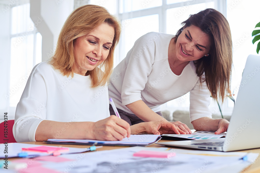 Couple of pretty businesswomen working and taking notes