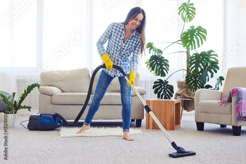 Slim woman cleaning with vacuum cleaner carpet photo