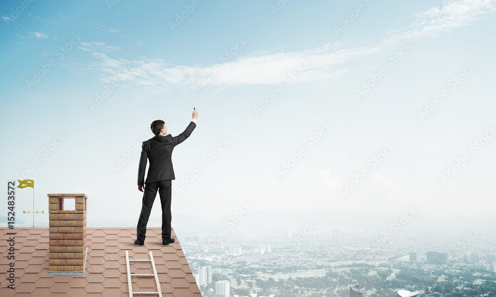 Businessman on house roof touch empty space. Mixed media Businessman on house roof touch empty space. Mixed media
