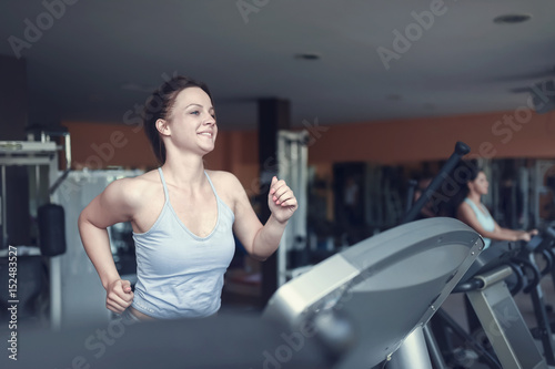 Attractive girl doing exercise on running track in the gym