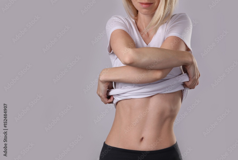 Woman taking off white t-shirt . Healthy, shape female body,, waist,  perfect abdomen muscles. Sport, fitness, Dieting results, active lifestyle  concept Stock Photo | Adobe Stock