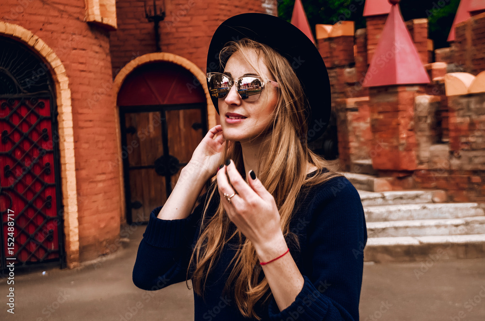 Obraz premium The blonde straightens her hair. She wore a hat and sunglasses