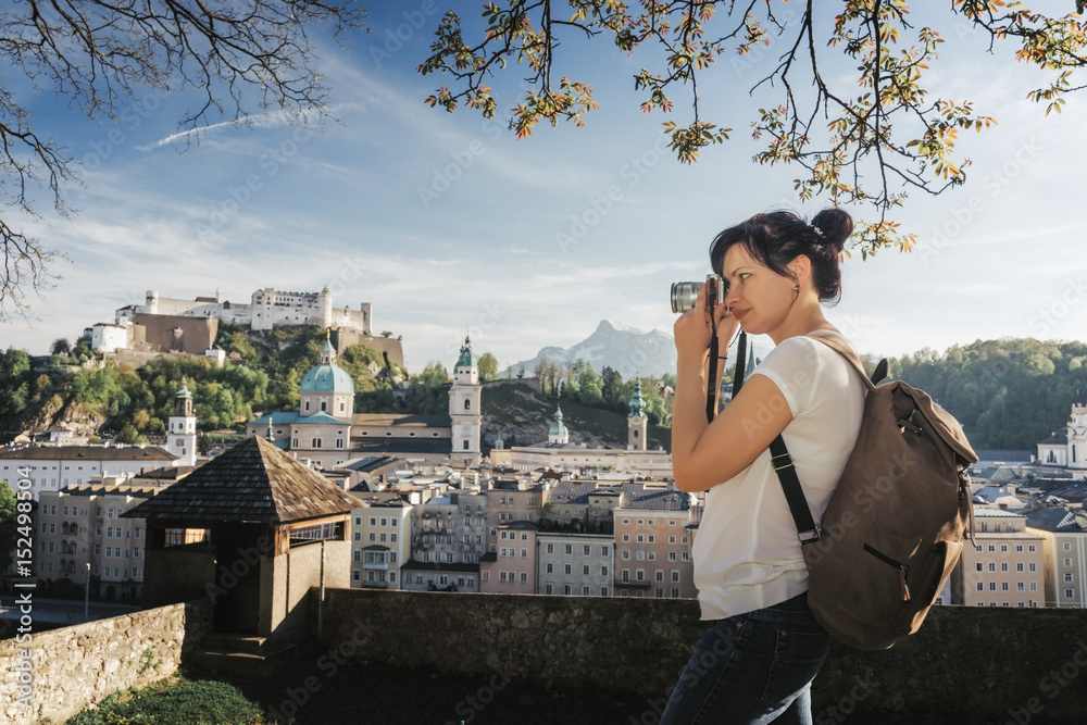 Austria. Salzburg. A young tourist girl takes pictures of the historic center of Salzburg UNESCO World Cultural Heritage