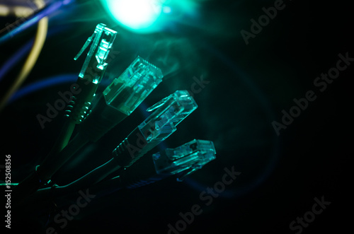Network switch and ethernet cables, symbol of global communications. Colored network cables on dark background with lights and smoke. Selective focus