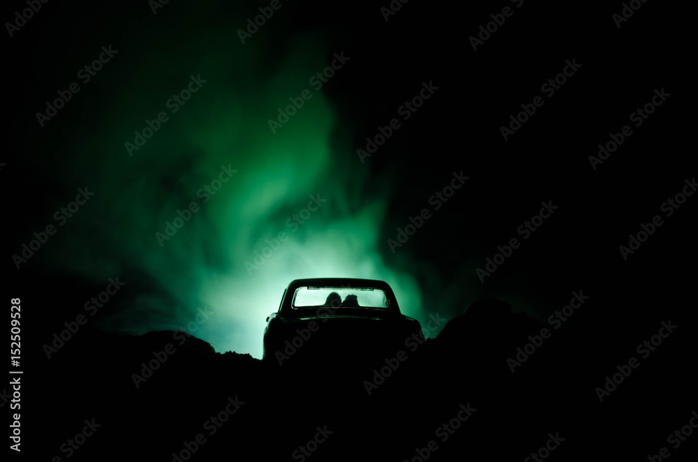 silhouette of car with couple inside on dark background with lights and smoke. Romantic scene. Love concept