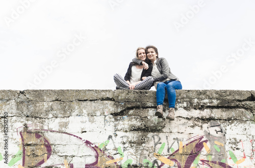 Two girls sit on a large wall