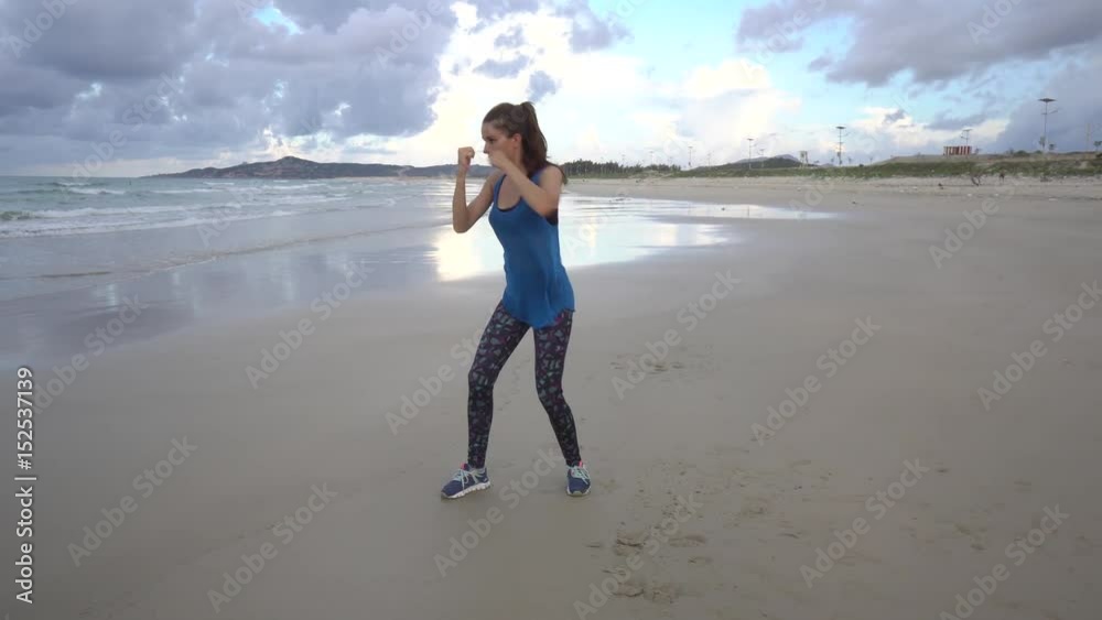 Athlete outline boxing into air on sea shore beach on sunset. Attractive female with long brown hair hit with hands, working out, do sports in the evening. Fit sporty Athlete outline boxing into air on sea shore beach on sunset. Attractive female with long brown hair hit with hands, working out, do sports in the evening. Fit sporty