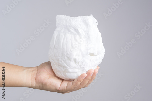 Hand holding used baby diaper