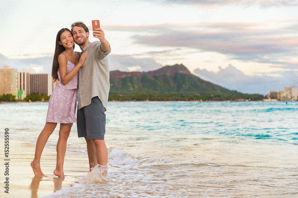 Φωτογραφία Couple walking on beach at sunset taking selfie picture on mobile phone relaxing together on Waikiki beach, Honolulu, Hawaii travel vacation